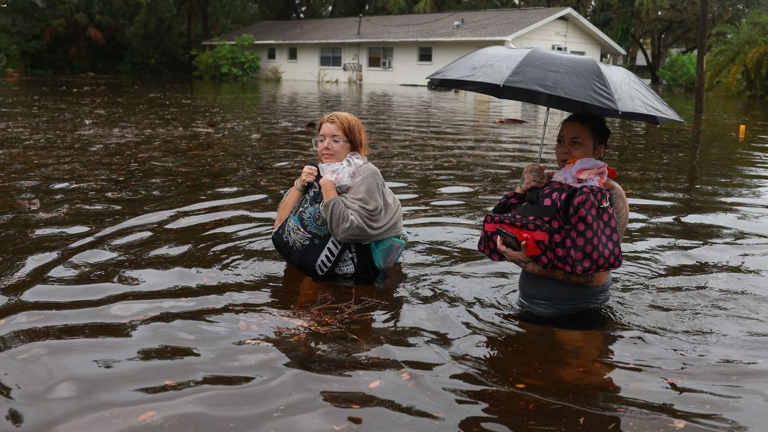 Makatla Ritchter, left, and her mother, Keiphra Line, wade through floodwaters after having to evacuate their home in Tarpon Springs on August 30.
