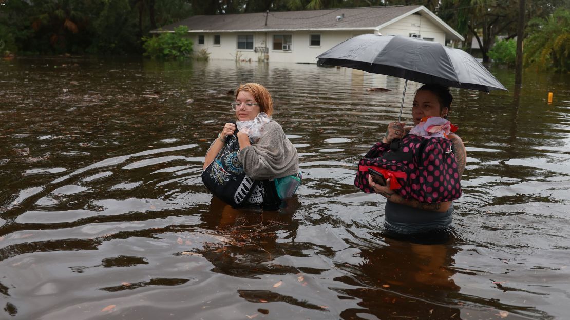 Makatla Ritchter, left, and her mother Keiphra Line wade through floodwater Wednesday in Tarpon Springs, Florida.