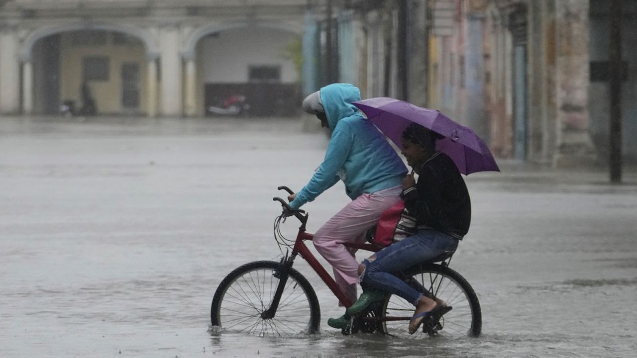 Commuters cycle through a street flooded by rain brought by Hurricane Idalia in Havana, Cuba, early Tuesday, August 29, 2023. 