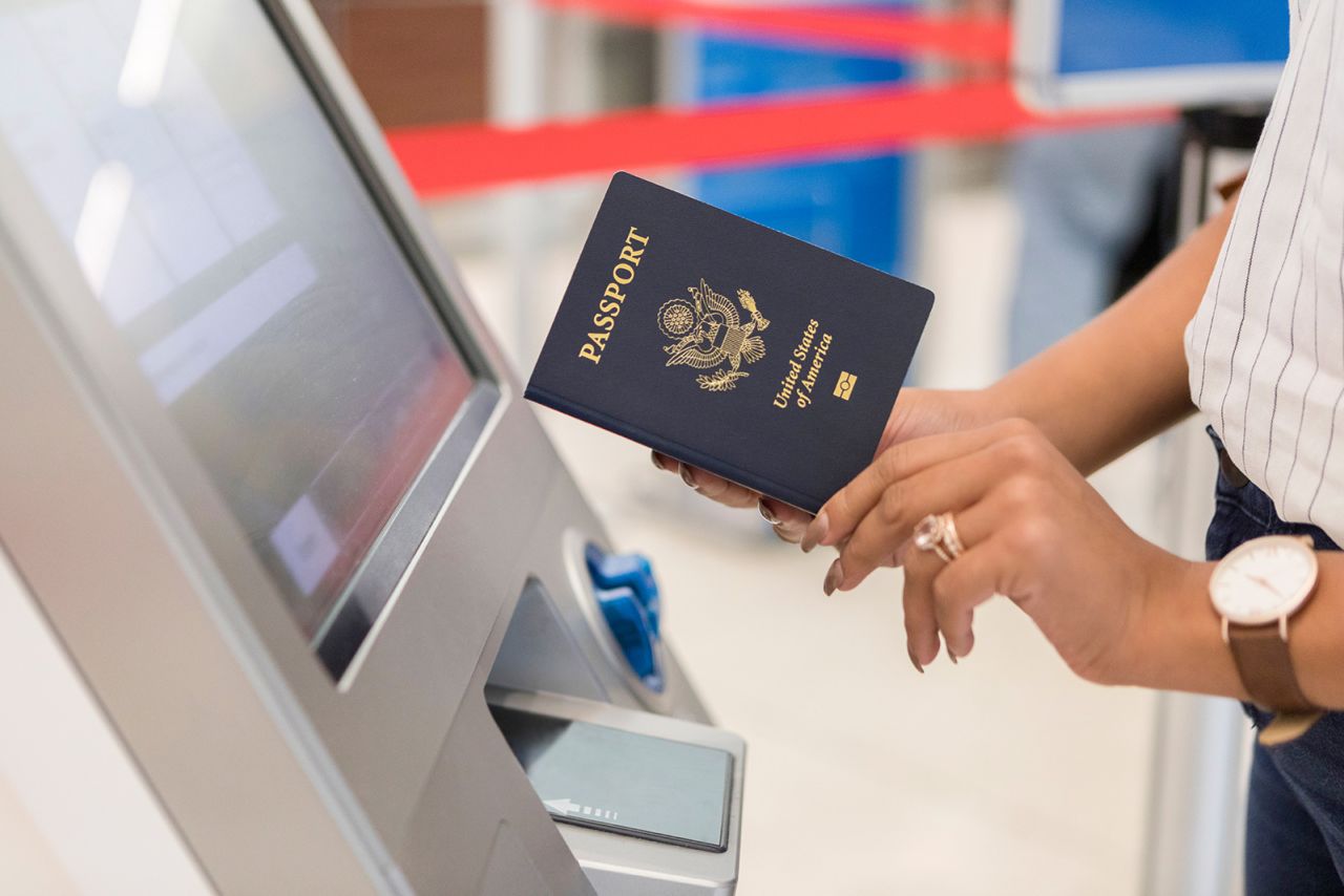 Unrecognizable business traveler uses an automated passport control kiosk at an international airport.