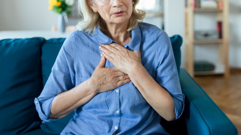 Senior Woman Suffering From Chest Pain While Sitting on Sofa at Home. Old Age, Health Problem, Vision and People Concept. Heart Attack Concept. Elderly Woman Suffering From Chest Pain Indoor