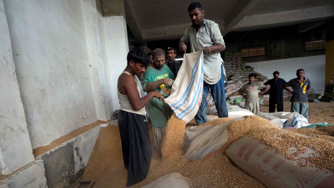 Pakistani workers sort the wheat in a warehouse in Karachi, Pakistan, on July 26, 2023.