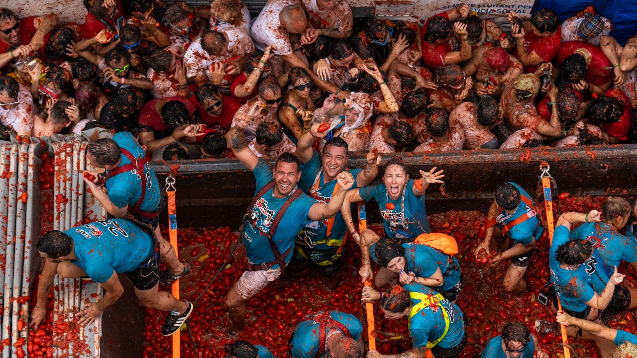 BUNOL, SPAIN - AUGUST 30: Revellers pose for photographers as they arrive at the town hall square in the back of a lorry containing tomatoes during the annual Tomatina festival on August 30, 2023 in Bunol, Spain. Spain's tomato throwing party in the streets of Bunol, Valencia brings together almost 20,000 people, with some 150,000 kilos of tomatoes thrown each year, this year with a backdrop of high food prices affected by Spain's historic drought. (Photo by Zowy Voeten/Getty Images)