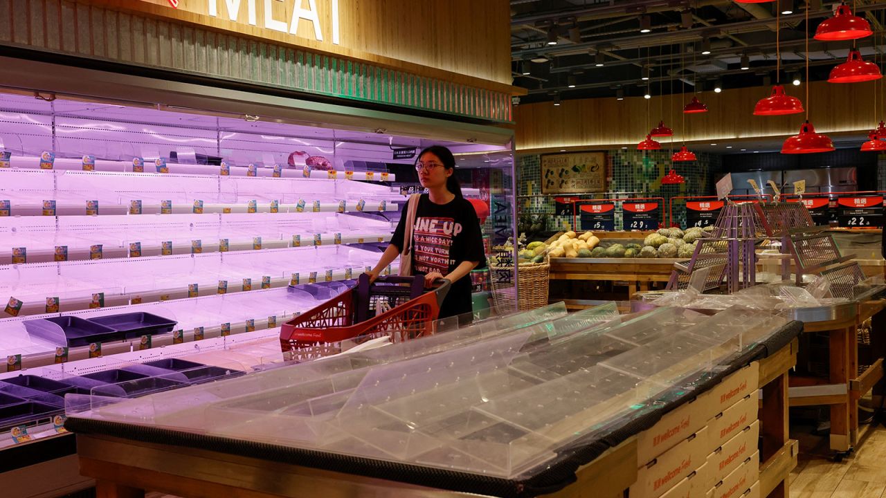 Customers walk past nearly empty shelves at a supermarket as Typhoon Saola approaches Hong Kong on August 31.
