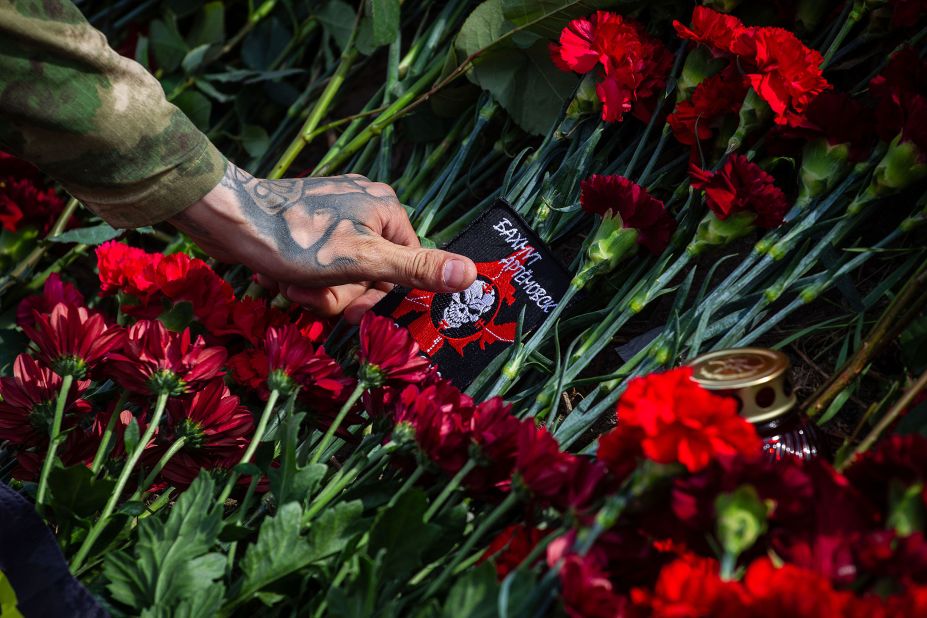 A Wagner group member lays a patch at a memorial to <a href="https://www.cnn.com/2023/08/27/europe/yevgeny-prigozhin-confirmed-dead-by-russia-intl/index.html" target="_blank">Yevgeny Prigozhin</a> in Saint Petersburg, Russia, on Wednesday, August 23. After genetic testing, Russian investigators confirmed Sunday that Wagner boss Prigozhin was among the people killed when their plane crashed in Russia last week.
