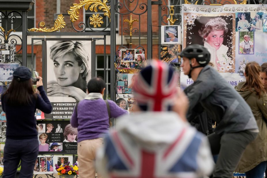 People look at pictures of Princess Diana at the gates of Kensington Palace in London on Thursday, August 31, the anniversary of her death.