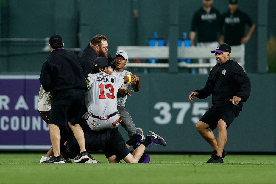 A fan charges at Atlanta Braves right fielder Ronald Acuna Jr. as grounds crew detain another fan during a game against the Colorado Rockies in Denver on Monday, August 28.