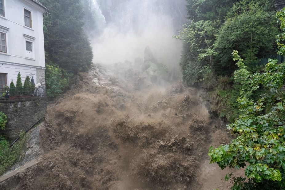 Muddy water flows past a waterfall in the center of Bad Gastein, Austria, on Monday, August 28. Authorities in the Tyrol and Salzburg provinces in western Austria put people on alert on Monday amid flooding and landslide risks due to heavy rains.