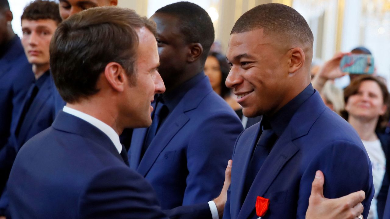France's president Emmanuel Macron (L) embraces France's forward Kylian Mbappe (R) during a ceremony to award French 2018 football World Cup winners with the Legion of Honour at the Elysee Palace in Paris. - Kylian Mbappe made the startling revelation on May 23, 2022 that he had talked over his potential transfer to Real Madrid with Emmanuel Macron, saying he appreciated the 