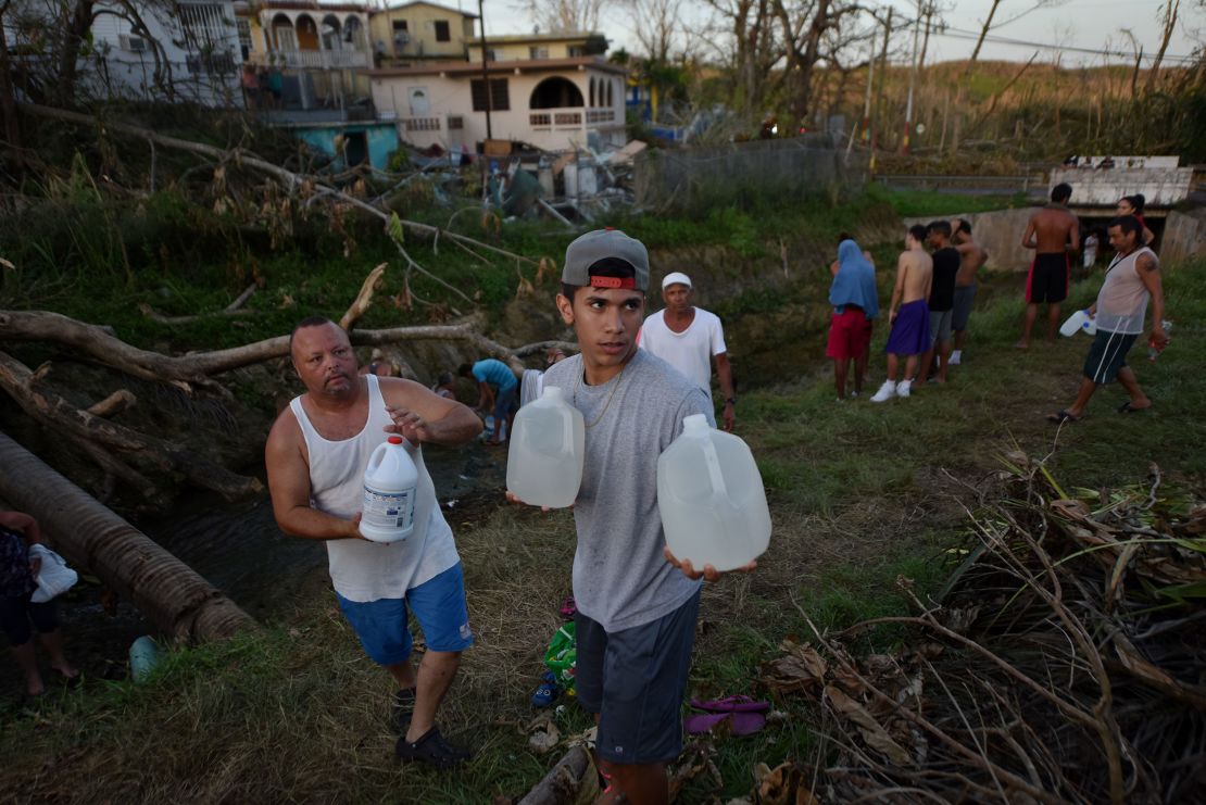 People carry water in bottles retrieved from a canal due to lack of water following passage of Hurricane Maria in Puerto Rico in September 2017.