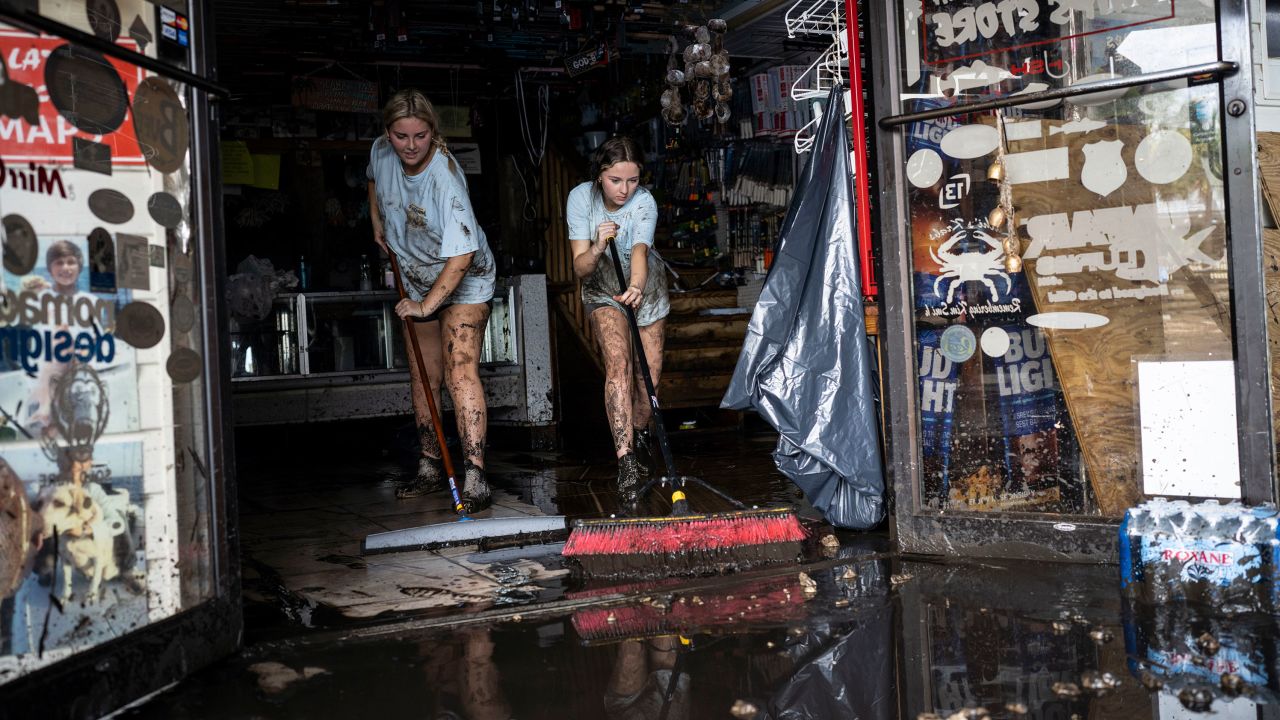 Katie Cole, left, and sister Savannah Cole clean mud out of the Sea Hag Marina gift shop, where they work as cashiers, in Steinhatchee, Florida on Thursday.