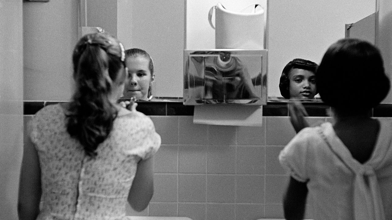 USA. Virginia. A black girl and a white girl make up in the ladies room before an integration dinner party during the civil rights strike in America. 1958.