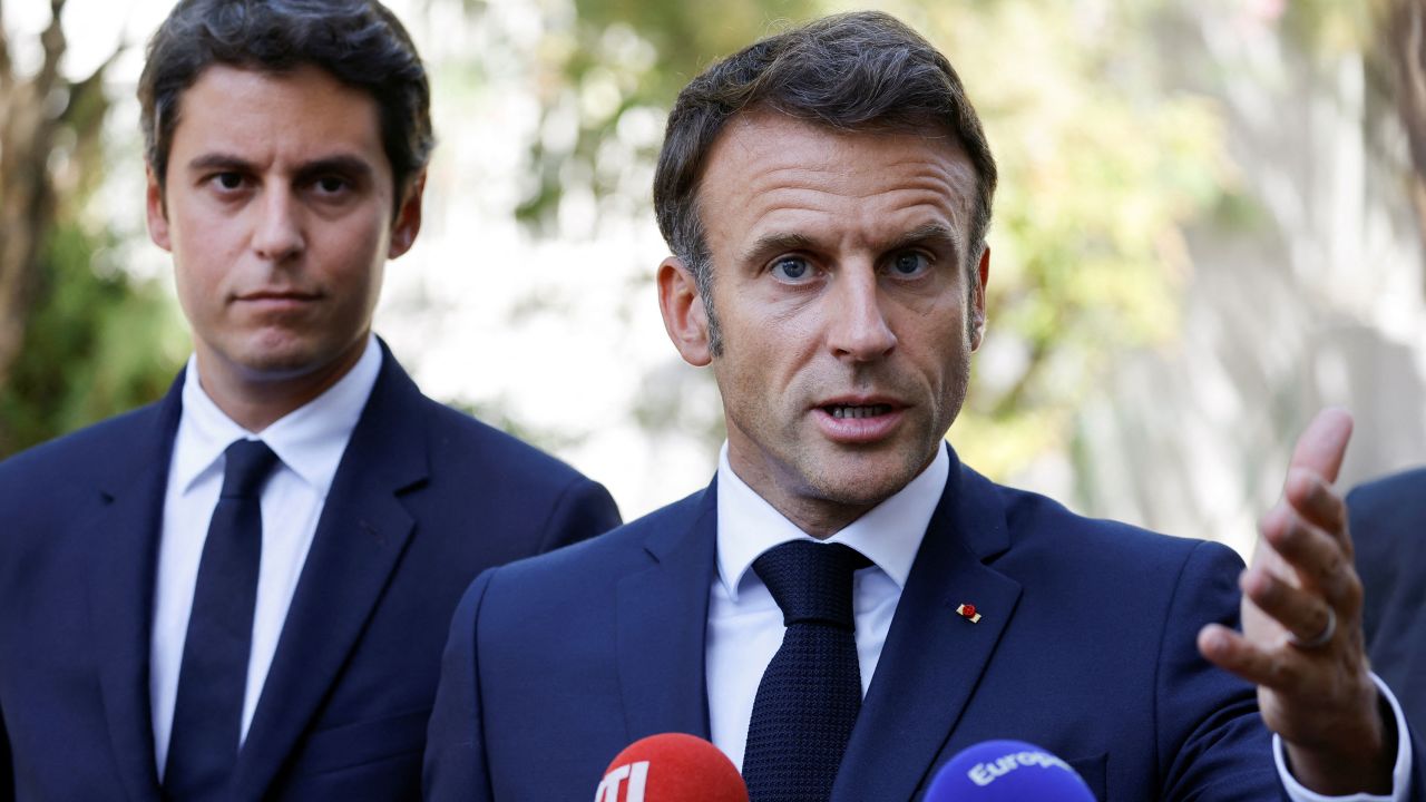 French President Emmanuel Macron gestures as he addresses the audience next to French Education and Youth Minister Gabriel Attal on September 1, 2023.