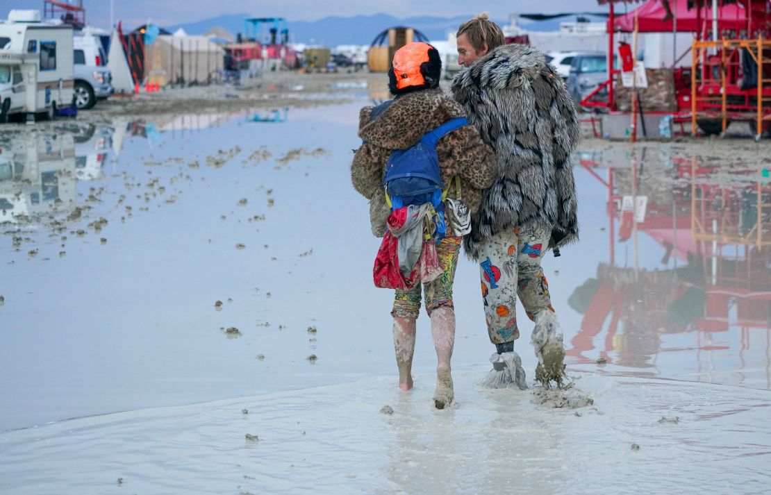 Burning Man attendees walk through the mud on Saturday.
