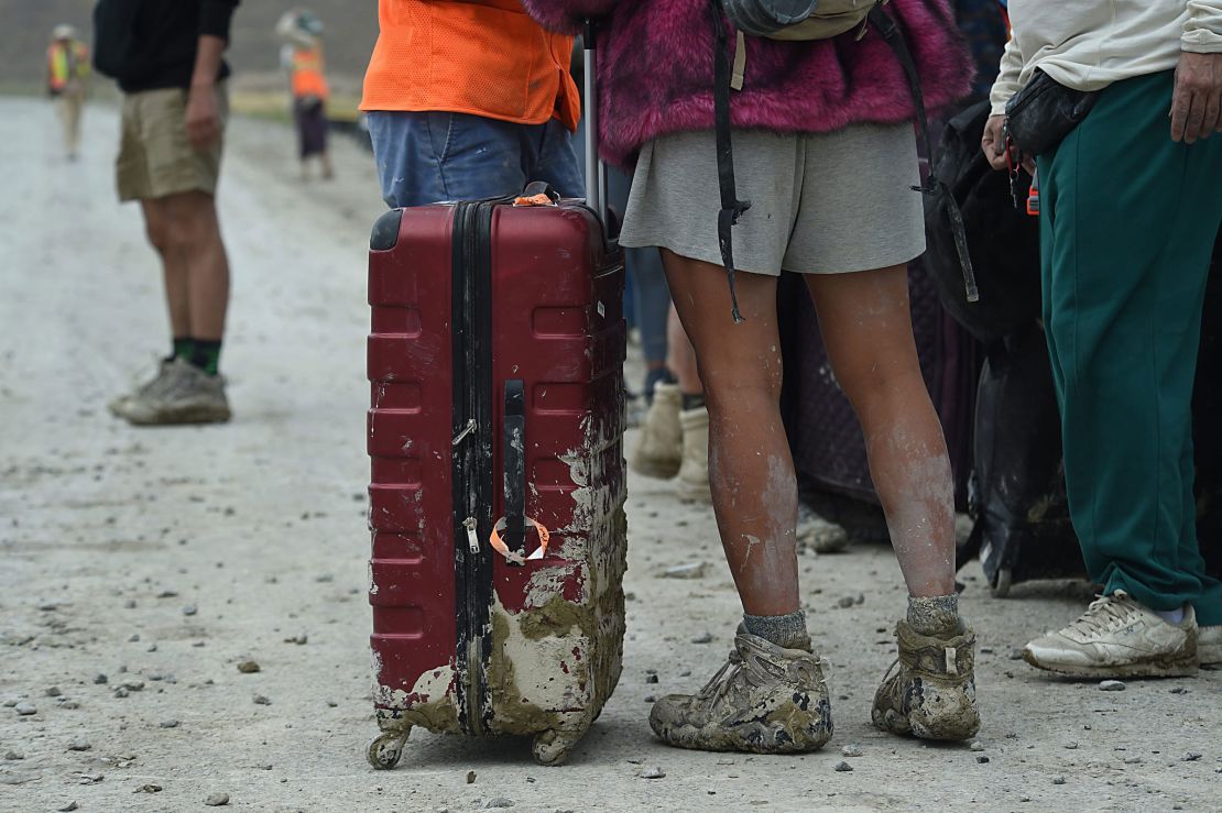 A person with a muddy suitcase waits to leave the Burning Man site on Sept. 3, 2023.