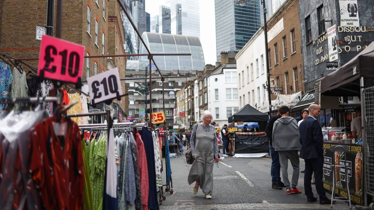 Пазаруващите разглеждат щандове в Petticoat Lane Market на фона на финансовия район на Лондон на 11 август 2023 г.