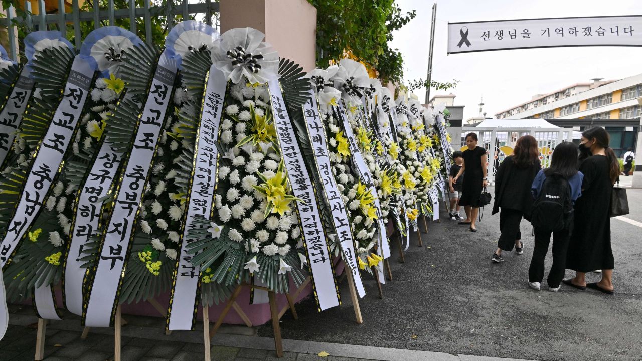 Mourners walk past funeral wreaths in front of the main gate of Seoul Seoi Elementary School in Seoul on September 4, 2023.