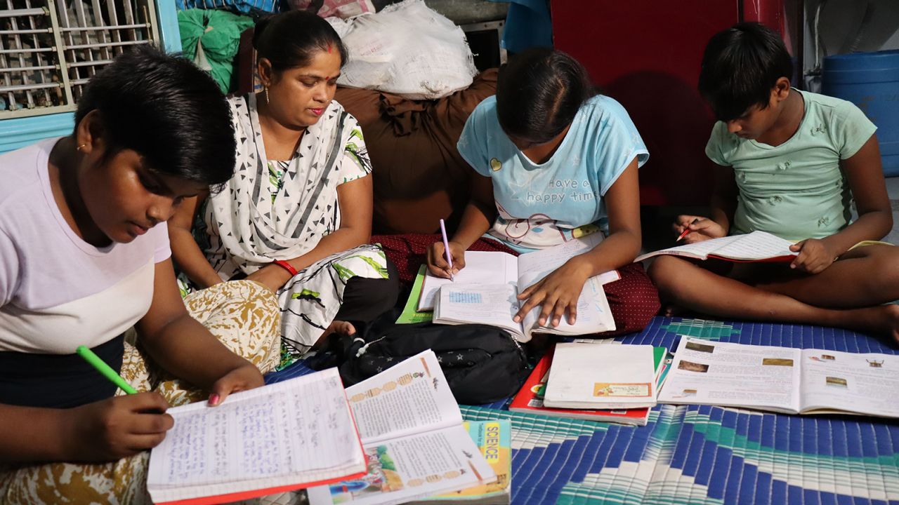 Savita helps her children with their homework in a makeshift home in Delhi.