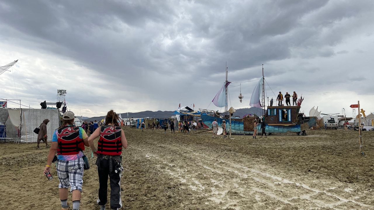 Participants walk across the muddy desert plains Saturday at the Burning Man festival site.