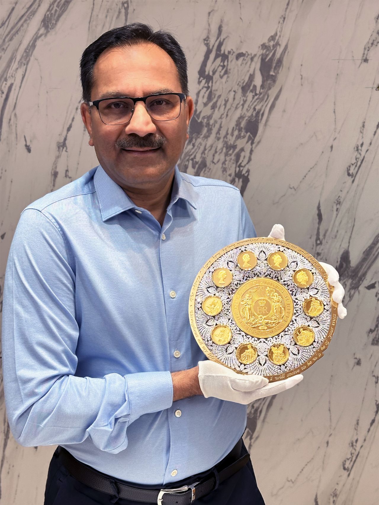 Businessman Sanjiv Mehta, who acquired the rights to the East India Company in 2005, poses with the diamond-encrusted coin.