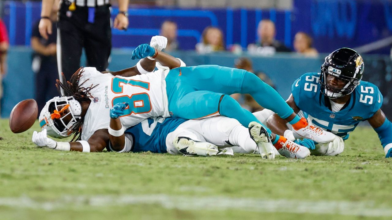 Miami Dolphins wide receiver Daewood Davis (87) rolls over after getting hit by Jacksonville Jaguars linebacker Dequan Jackson (55) and cornerback Kaleb Hayes during the fourth quarter of an NFL preseason football game Saturday, Aug. 26, 2023, in Jacksonville, Fla. (Al Diaz/Miami Herald via AP)