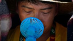 A World Youth Day volunteer uses a small fan to cool off from the intense heat, as he waits ahead of the Pope Francis arrival at Passeio Marítimo in Algés, just outside Lisbon, Aug. 6, 2023. 