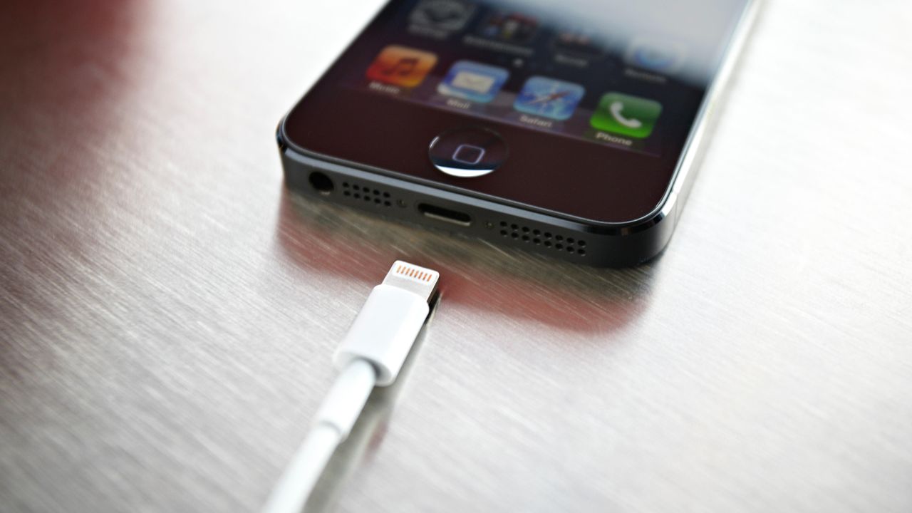 A newly released Apple iPhone 5 sits on a coffee shop countertop next to Apple's lightning connection cable in September 2012.