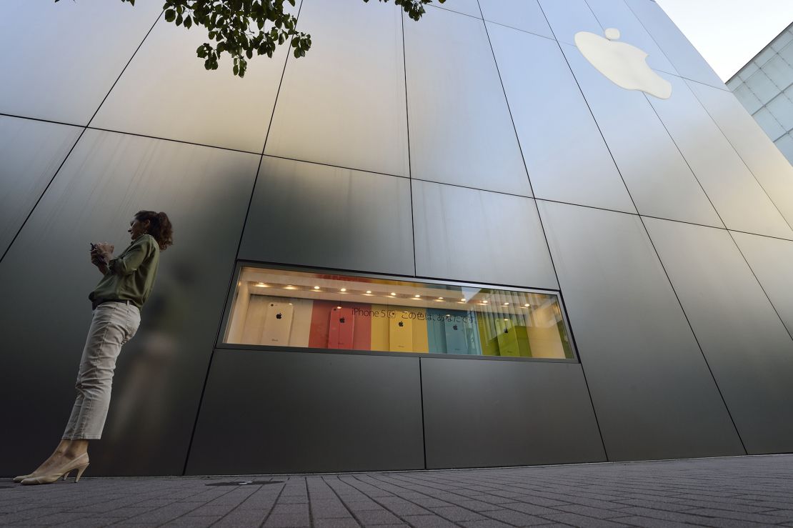 A woman uses her smartphone in front of a display for the Apple iPhone 5C outside the company's store in the Ginza district of Tokyo, Japan, on September 20, 2013.