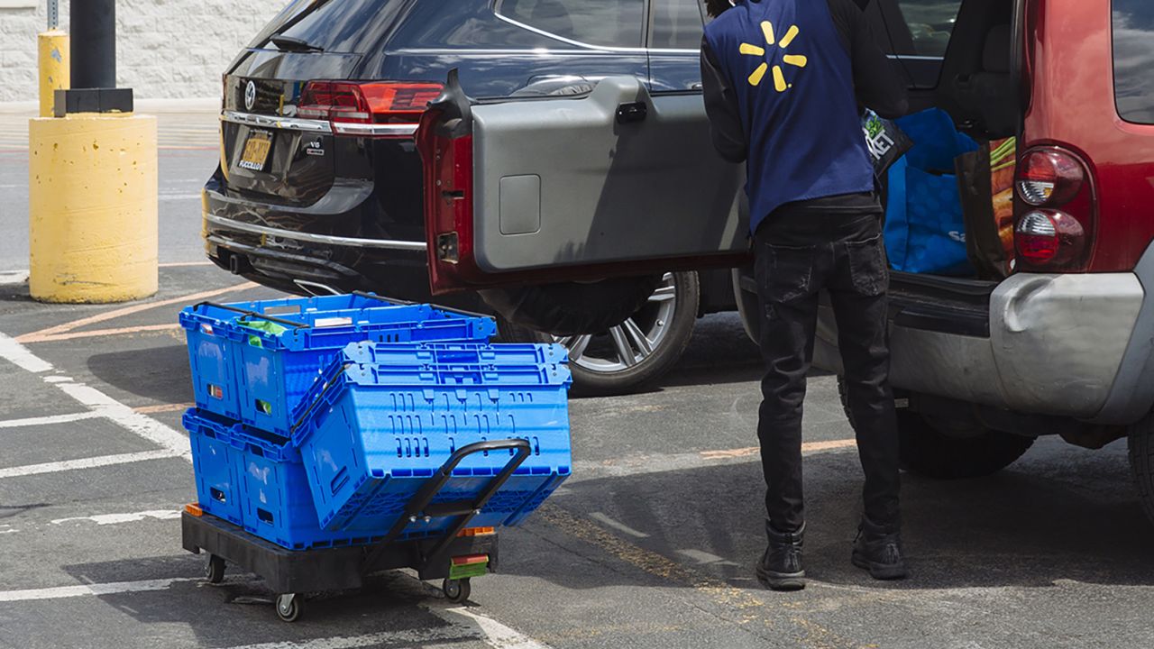 A worker delivers groceries to a customer's vehicle outside a Walmart Inc. store in Amsterdam, New York, U.S., on Friday, May 15, 2020. 