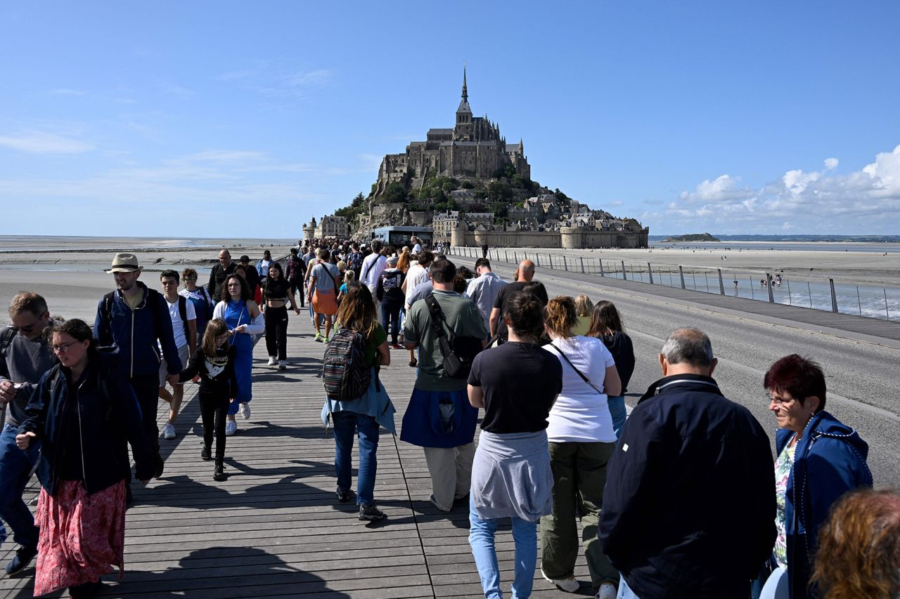 Tourits queue up to catch buses to leave the site and reach the parking lots at Le Mont-Saint-Michel, northwestern France, on July 25, 2023. (Photo by Damien MEYER / AFP) (Photo by DAMIEN MEYER/AFP via Getty Images)