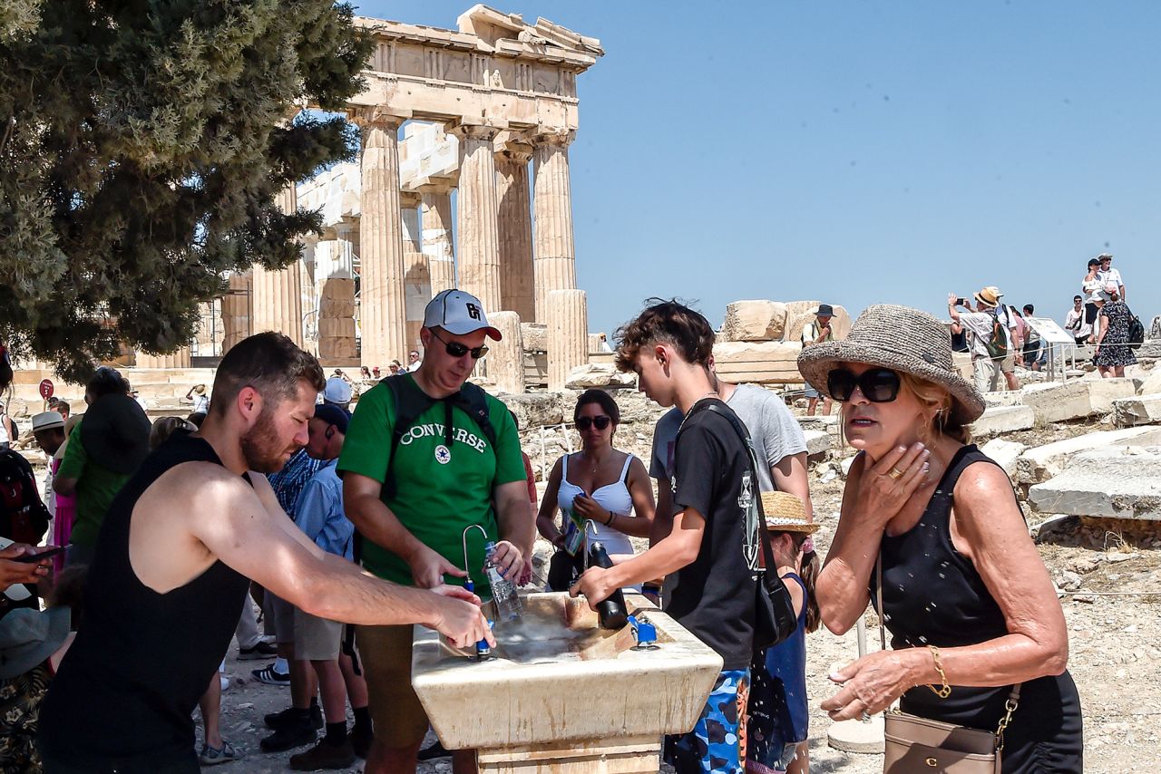 ATHENS, GREECE - JULY 20: Tourists refresh with water in front of the five century BC Parthenon temple at the Acropolis hill during a heat wave on July 20, 2023 in Athens, Greece. The Acropolis of Athens and other archaeological sites in Greece announced reduced opening hours due to the heatwave conditions. Parts of Europe continue to experience extreme conditions of the Cerberus heatwave, dubbed Charon. (Photo by Milos Bicanski/Getty Images)