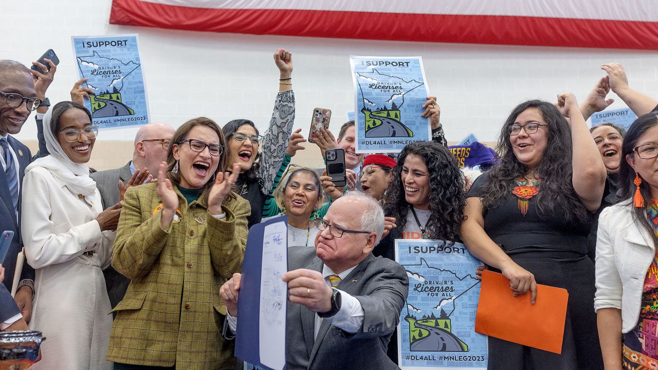 Minnesota Gov. Tim Walz, center, signs the Driver's Licenses for All bill on March 7.