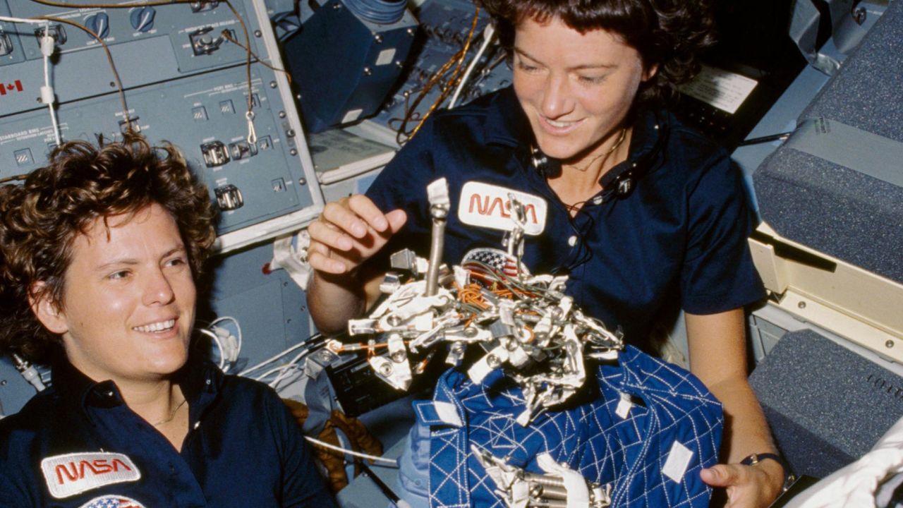 41G-07-021 (5-13 October 1984) --- Astronauts Kathryn D. Sullivan, left, and Sally K. Ride show off what appears to be a "bag of worms", a product of their creativity. The "bag" is a sleep restraint and the majority of the "worms" are springs and clips used with the sleep restraint in its normal application. Clamps, a bungee cord and Velcro strips are other recognizable items in the "creation".
Date Created:1984-10-06