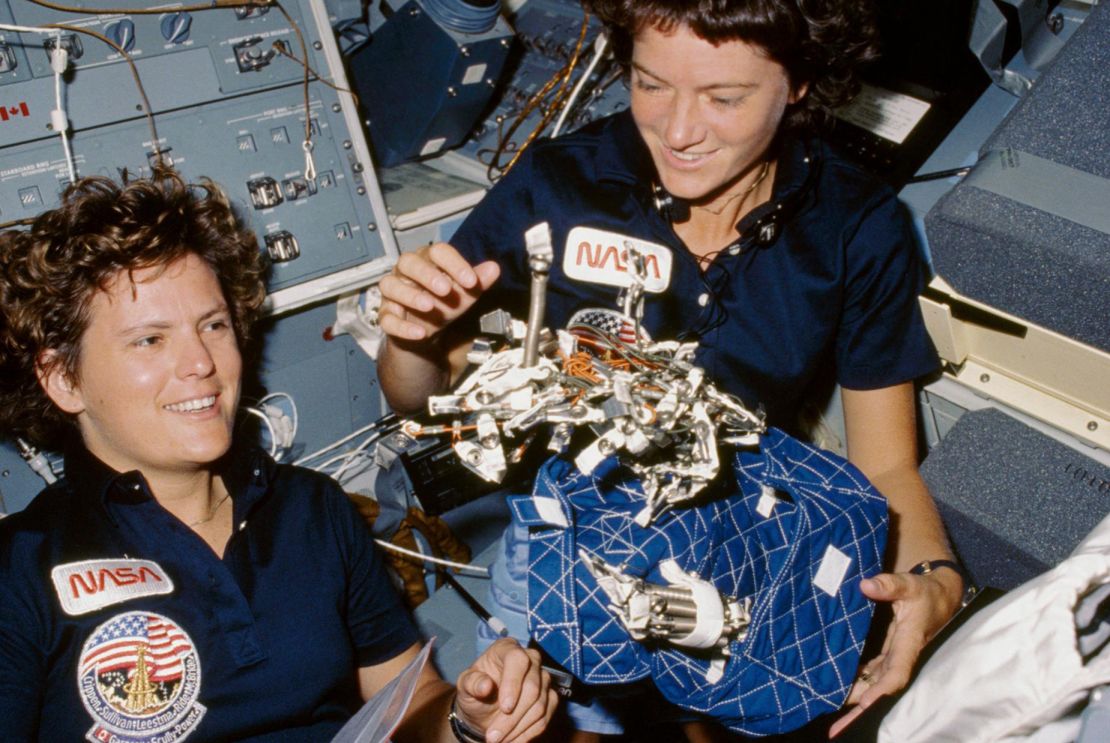 41G-07-021 (5-13 October 1984) --- Astronauts Kathryn D. Sullivan, left, and Sally K. Ride show off what appears to be a "bag of worms", a product of their creativity. The "bag" is a sleep restraint and the majority of the "worms" are springs and clips used with the sleep restraint in its normal application. Clamps, a bungee cord and Velcro strips are other recognizable items in the "creation".
Date Created:1984-10-06