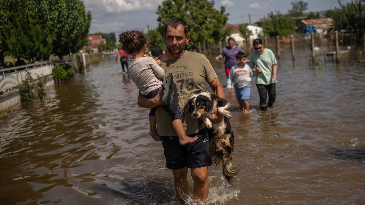 Un hombre carga a una niña y un perro en el pueblo inundado de Palamas, en el centro de Grecia, el 8 de septiembre de 2023.