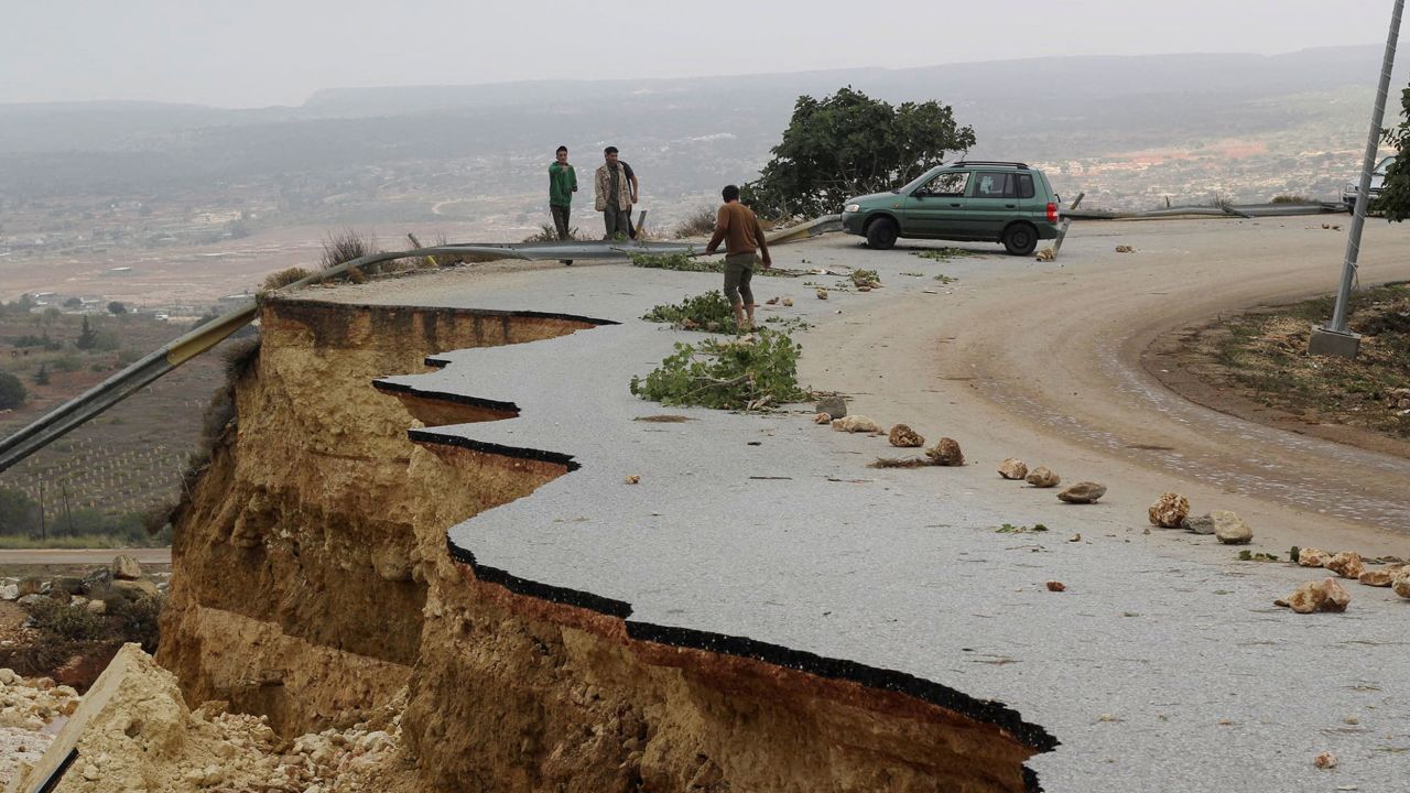 People stand in a damaged road as a powerful storm and heavy rainfall flooded hit Shahhat city, Libya, September 11, 2023.
