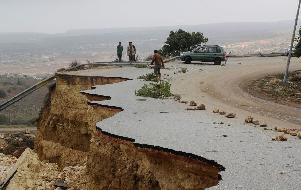 People stand on a damaged road in Shahhat, Libya, on Monday, September 11.