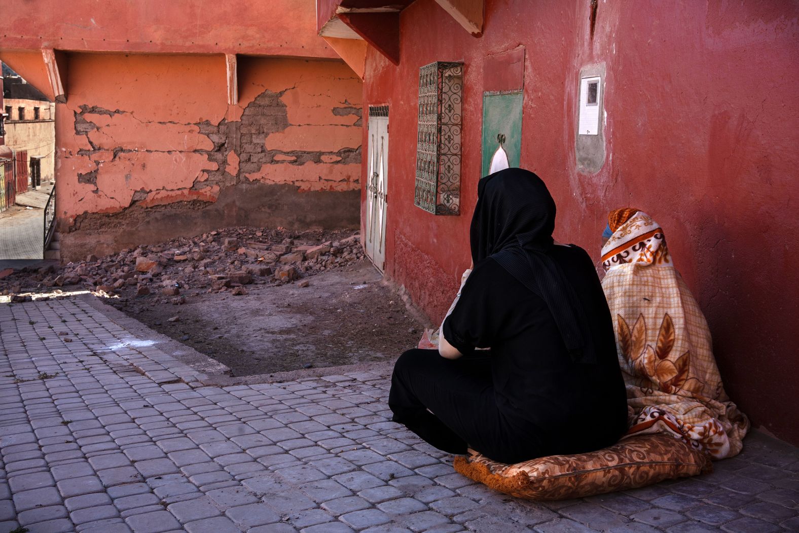 Two women who lost their homes sit outside in Moulay Brahim on Monday. People are sleeping on the streets, Borrazás said, and as of Monday afternoon they were not yet receiving humanitarian aid.
