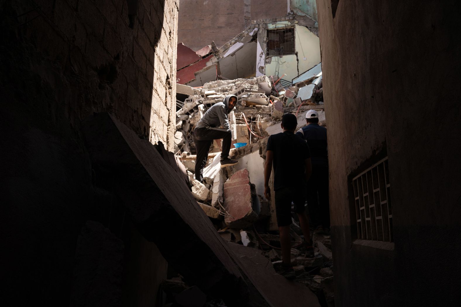 Rescuers and local residents try to extract the body of an 84-year-old woman who was under the rubble of her house in Azizmiz.