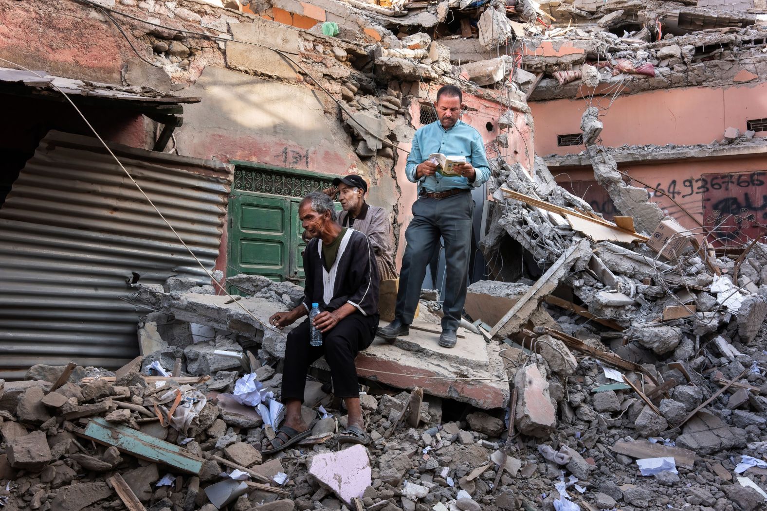 A man reads a book on top of a collapsed house in Amizmiz.