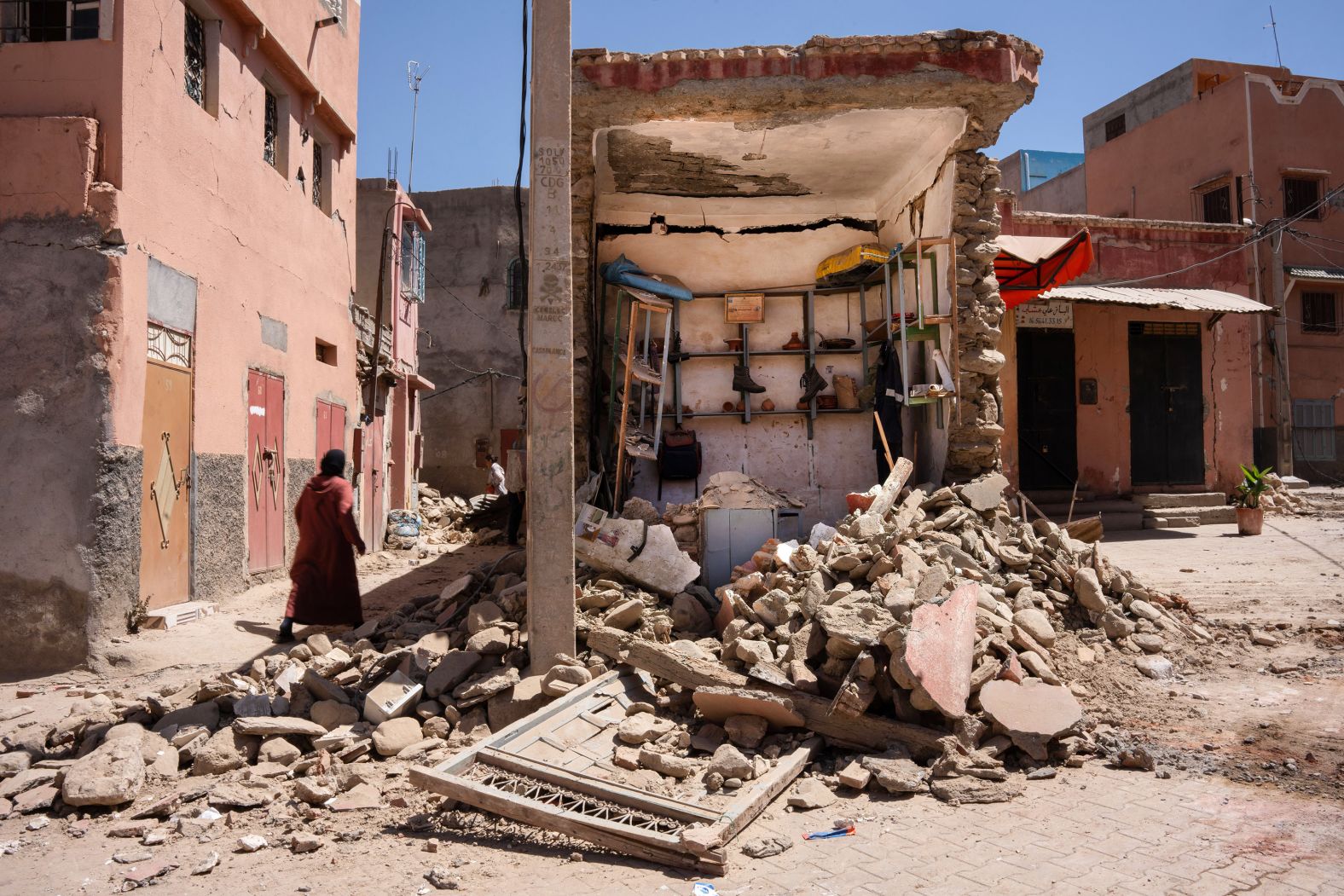 A woman walks next to a destroyed shop in Amizmiz.