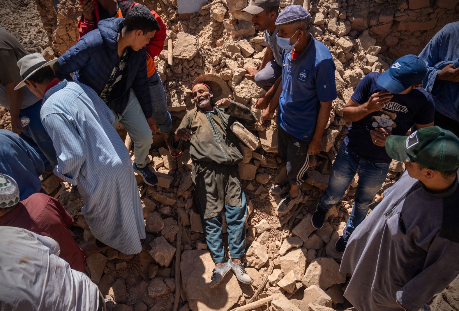 A man is overcome with grief as the body of his 30-year old son is removed from a collapsed house in Douzrou on September 11.