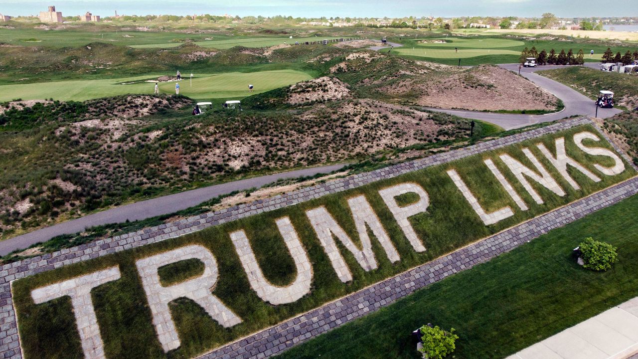 In this May 2021 photo, patrons play the links as a giant branding sign is displayed with flagstones at Trump Golf Links, at Ferry Point in the Bronx borough of New York.