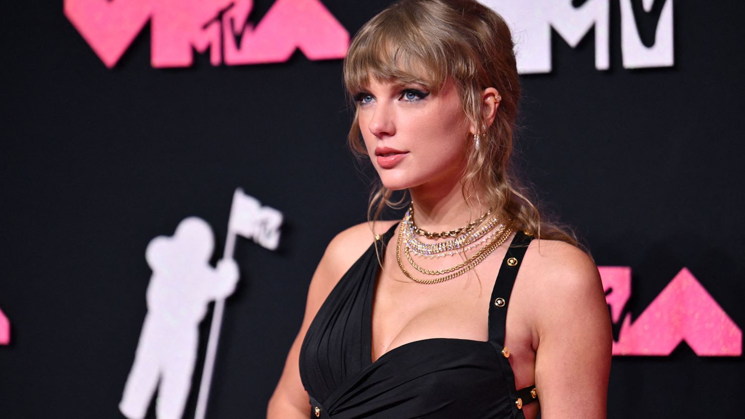 Taylor Swift arrived at the VMAs in a slinky, high-slit black Versace dress with gold button embellishments.