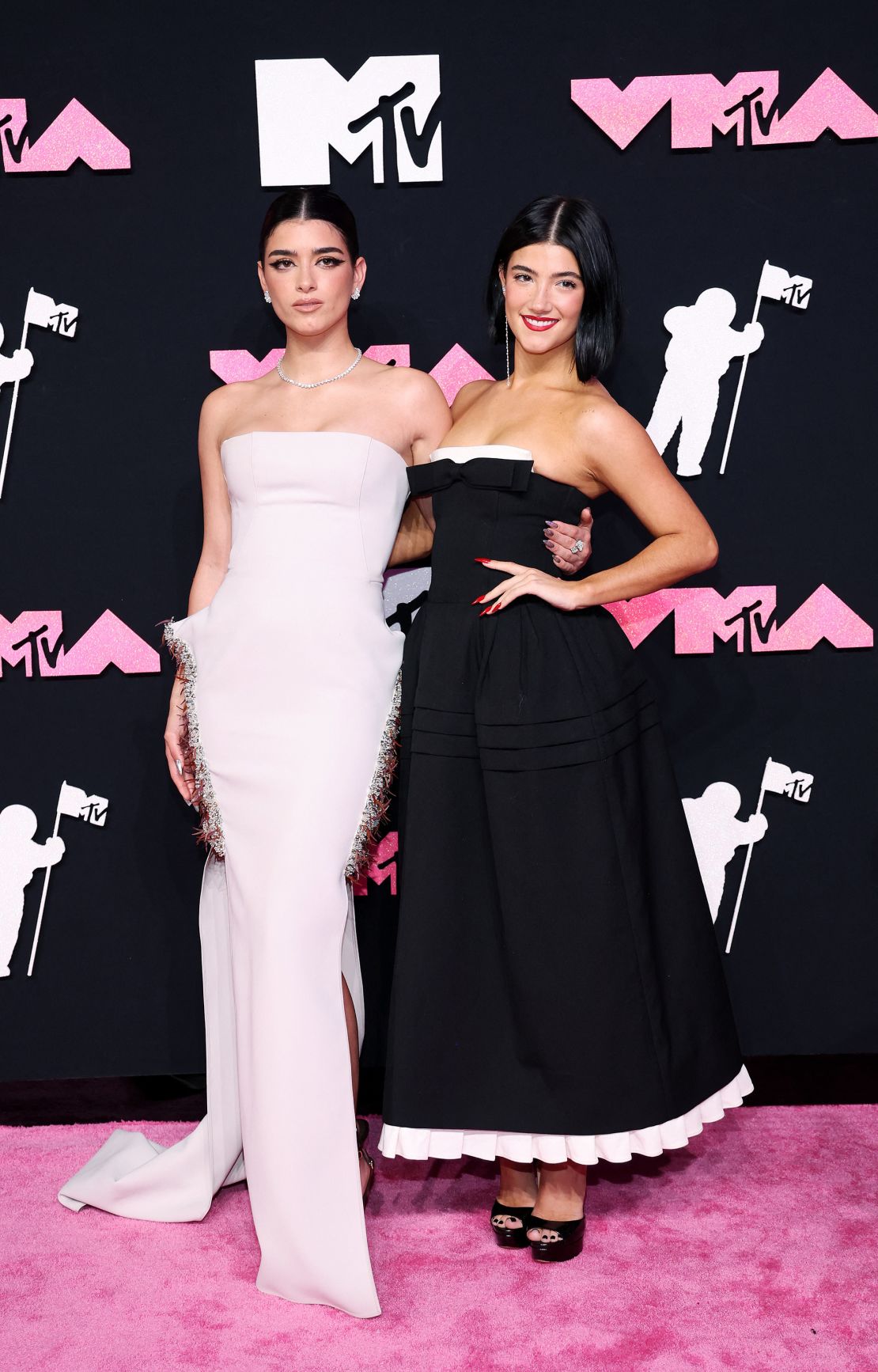 TikTok stars Dixie and Charli D'Amelio were a contrasting and complementary pair, with Dixie (left) in a white strapless Maticevski mermaid dress and Charli (right) in a black dress with playful white trim.