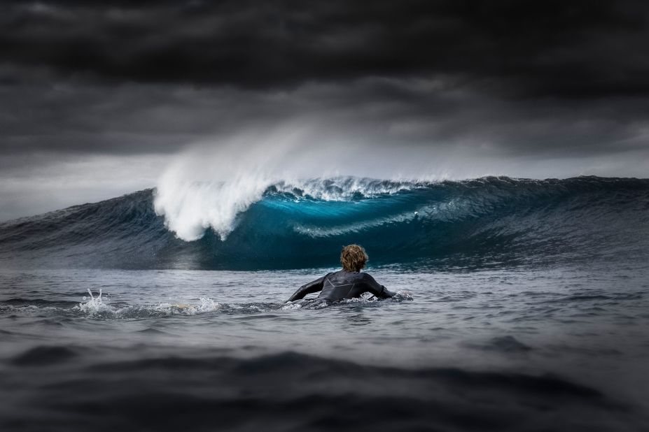 A bodyboarder paddles out to sea, while big storm clouds block the sun and create an electric blue color effect on the wave. This image taken in Western Australia landed Jarvis Smallman with the young ocean photographer of the year award.<br />