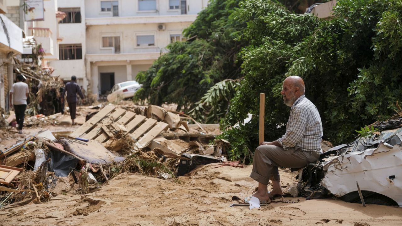 A man sits on a damaged car, after a powerful storm and heavy rainfall hit eastern Libya, on Tuesday.