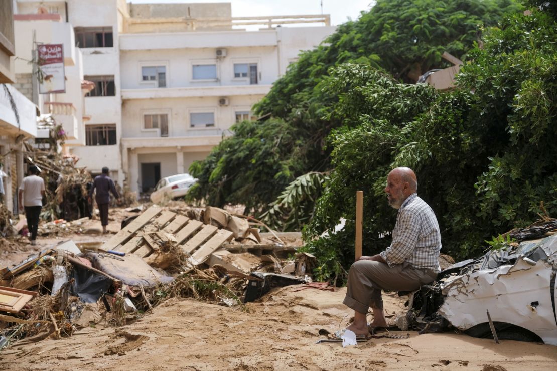 A man sits on a damaged car, after a powerful storm and heavy rainfall hit eastern Libya, on Tuesday.