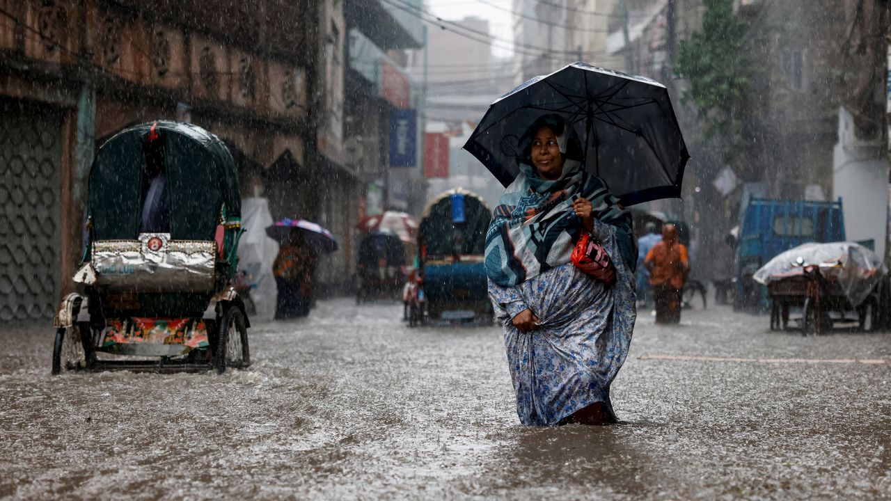 A woman holding an umbrella while walking along a flooded street during heavy rain in Dhaka, Bangladesh in June.