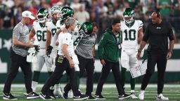 EAST RUTHERFORD, NEW JERSEY - SEPTEMBER 11: Quarterback Aaron Rodgers #8 of the New York Jets is helped off the field by team trainers after an injury during the first quarter of the NFL game against the Buffalo Bills at MetLife Stadium on September 11, 2023 in East Rutherford, New Jersey. (Photo by Elsa/Getty Images)